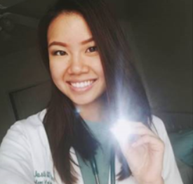 Justine Ker holding a flashlight in a white coat