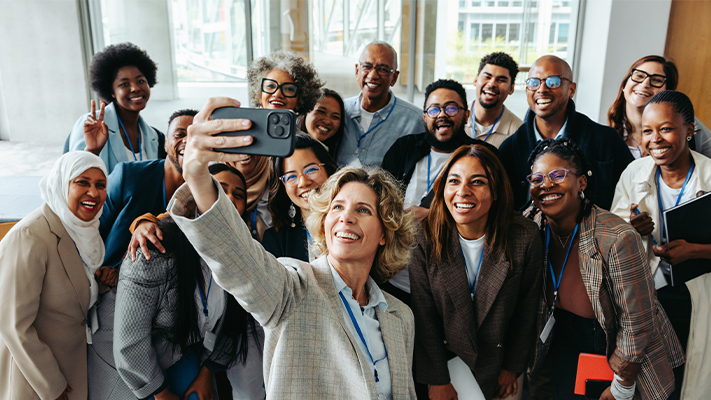 Group of conference attendees smiling and taking a selfie together.