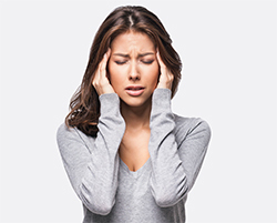 Woman rubbing her temples from headache pain